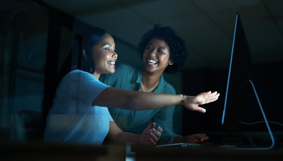 Twee jonge zakenvrouwen werken samen achter een computer tijdens een late avond op het werk