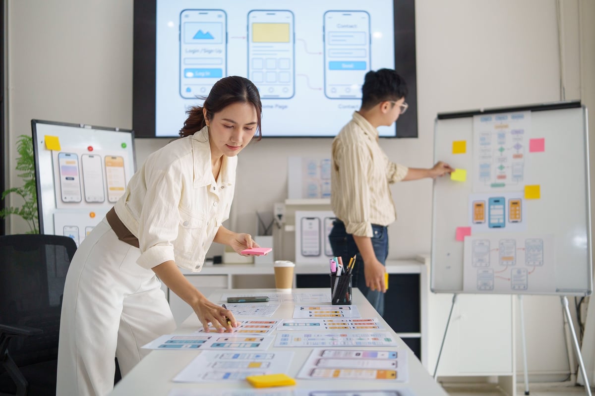 UX designer schrijft notities op plakbriefjes terwijl hij een mobiele app interface plant